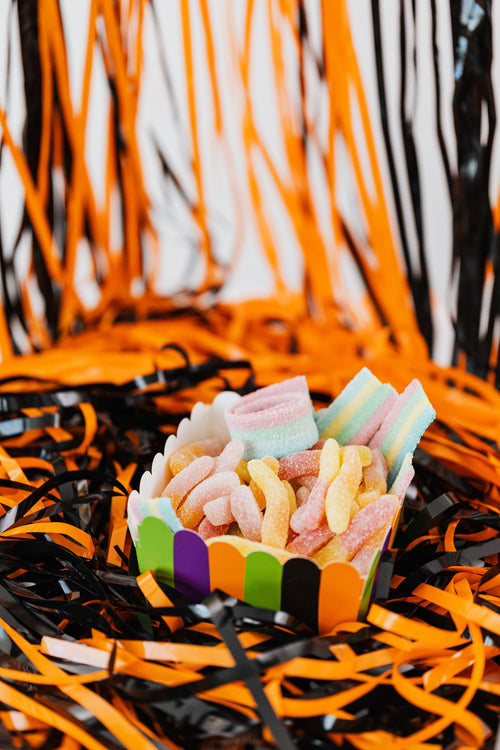 Coupelle de bonbons gélifiés acidulés sur un décor d'Halloween orange et noir