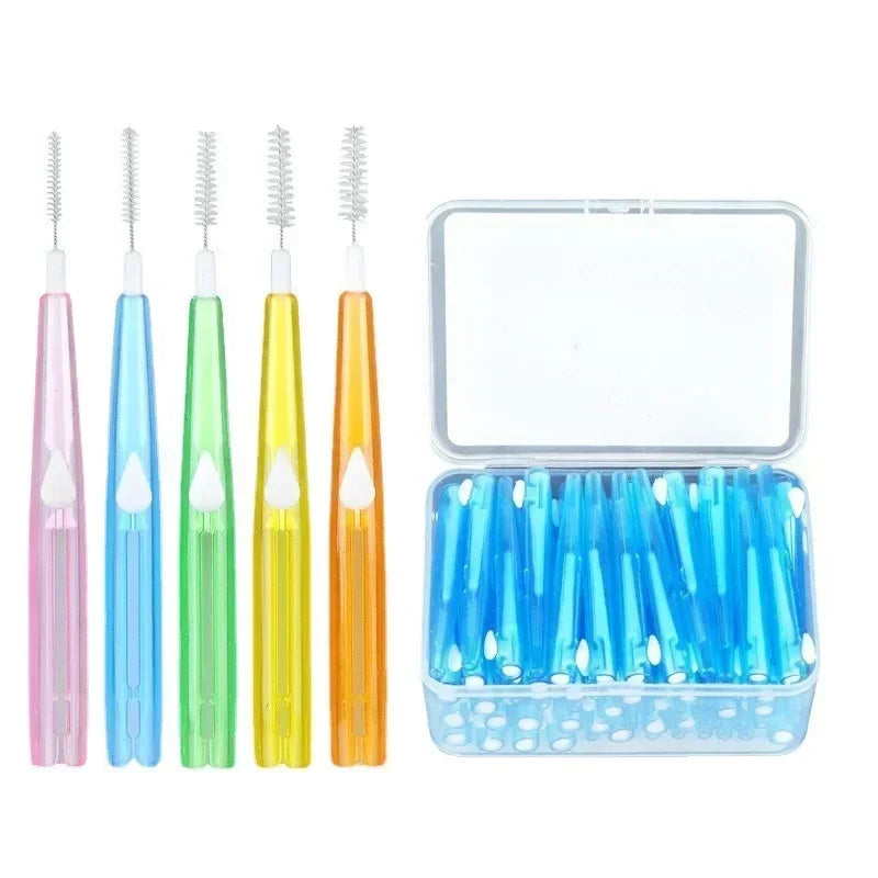 Cinq brossettes interdentaires rose, bleue, verte, jaune et orange à côté d’une boîte transparente remplie de brossettes bleues
