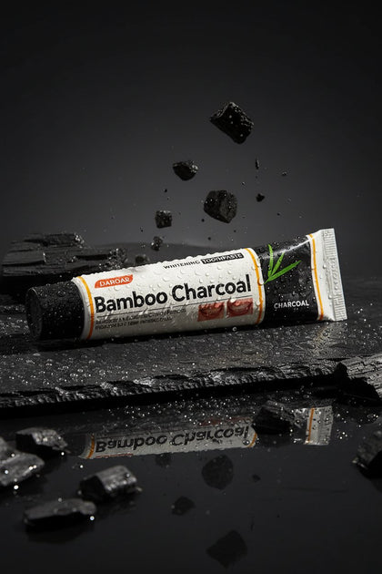 Dentifrice Charbon Actif Blancheur ÉclatDent sur une ardoise humide avec des éclats de charbon de bambou