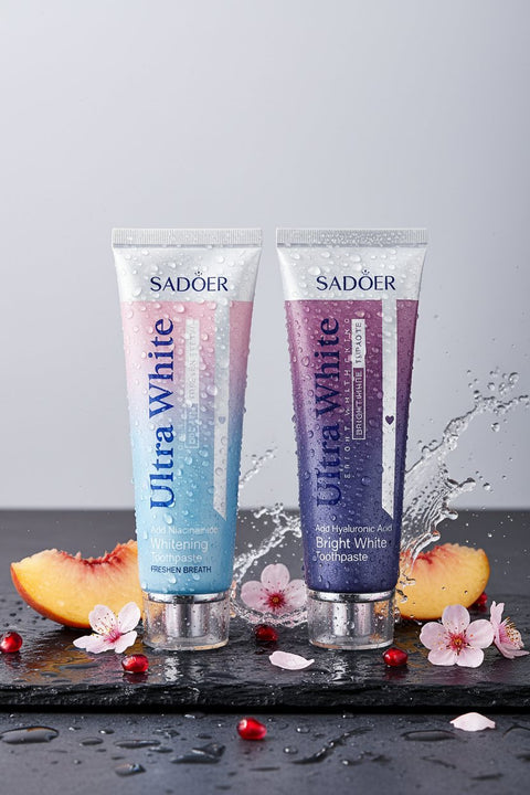 Pack Duo Ultra White ÉclatDent : les deux dentifrices sur une ardoise humide avec pêche, grenade et fleurs de cerisier
