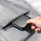 Black case slipped into the pocket of a grey fabric bag