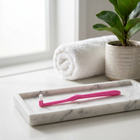 End-tuft toothbrush — on a white marble tray in a bright bathroom