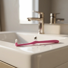 End-tuft toothbrush — on the edge of a white washbasin, morning light