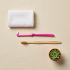 End-tuft toothbrush — flat lay on a cream background, minimalist composition