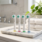 Testine compatibili Oral-B con ciuffo centrale — su un vassoio di marmo bianco in un bagno luminoso