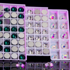 Strass dentaires en cristal à dos plat — sur fond noir, éclats de lumière violette et rose