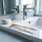 Gratte-langue en cuivre — au bord d'un lavabo blanc, lumière du matin