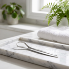 Gratte-langue en inox — sur un plateau en marbre blanc dans une salle de bain lumineuse