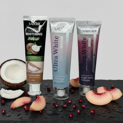 Pack Fruité & Douceur ÉclatDent : les trois dentifrices sur une ardoise humide avec coco, pêche et grains de grenade