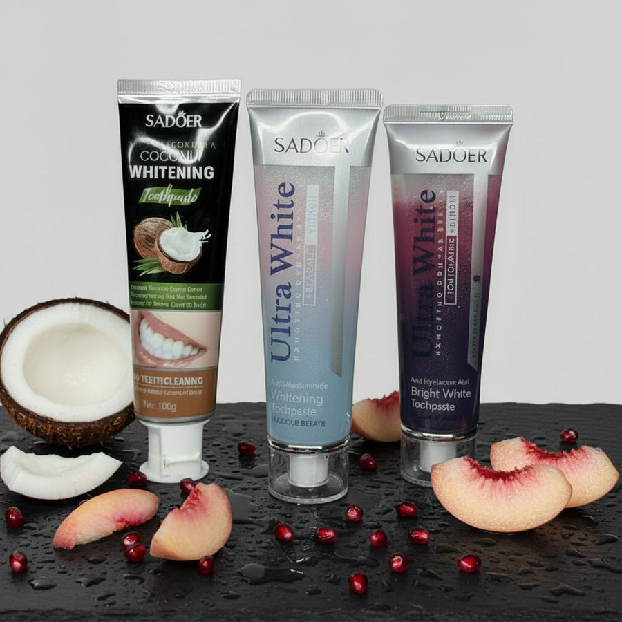 Pack Fruité & Douceur ÉclatDent : les trois dentifrices sur une ardoise humide avec coco, pêche et grains de grenade