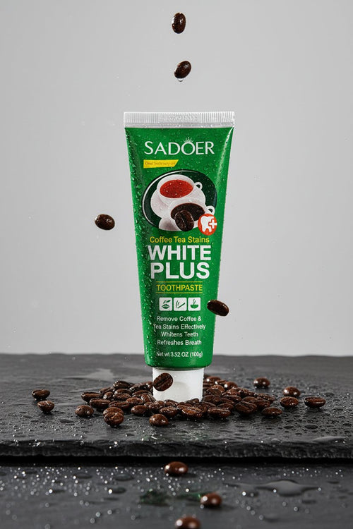 Dentifrice Anti-Taches Café ÉclatDent posé sur une ardoise humide entouré de grains de café