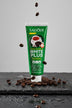 Dentifrice Anti-Taches Café ÉclatDent posé sur une ardoise humide entouré de grains de café