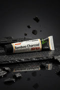 Dentifrice Charbon Actif Blancheur ÉclatDent sur une ardoise humide avec des éclats de charbon de bambou