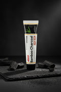 Dentifrice Charbon Actif Blancheur ÉclatDent sur une ardoise noire entouré de morceaux de charbon