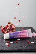 Dentifrice Grenade & Sakura ÉclatDent sur une ardoise humide avec grenade ouverte et pétales de cerisier