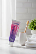 Dentifrice Grenade & Sakura ÉclatDent dans une salle de bain avec brosse à dents en bambou et serviettes