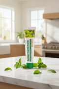 Dentifrice Classique Menthe ÉclatDent sur un plan de travail en marbre avec des feuilles de menthe