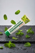 Dentifrice Classique Menthe ÉclatDent sur une ardoise humide avec des feuilles de menthe fraîche