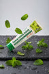 Dentifrice Classique Menthe ÉclatDent sur une ardoise humide avec des feuilles de menthe fraîche