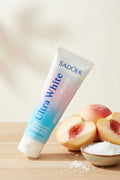 Dentifrice Pêche & Sel Marin ÉclatDent sur une table en bois avec des pêches fraîches et de la fleur de sel