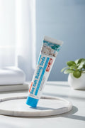 Dentifrice Sel Marin & Bicarbonate ÉclatDent sur un plateau blanc avec une plante verte en arrière-plan