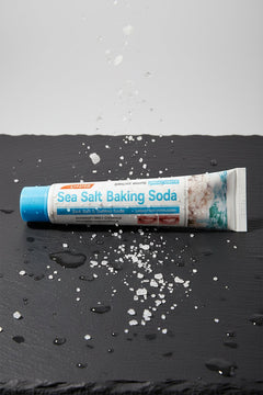 Sea Salt & Baking Soda Purifying ÉclatDent toothpaste on a wet slate with sea salt crystals