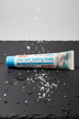 Dentifrice Sel Marin & Bicarbonate ÉclatDent sur une ardoise humide avec des cristaux de sel marin
