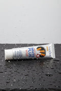 Dentifrice Anti-Taches Tabac ÉclatDent couché sur une ardoise noire couverte de gouttes d'eau