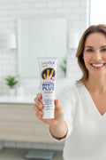 Femme souriante présentant le dentifrice Anti-Taches Tabac ÉclatDent dans une salle de bain