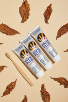 Pack Anti-Taches Tabac ÉclatDent vu de dessus sur fond beige : les trois tubes entourés de feuilles de tabac séchées