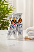 Pack Anti-Taches Tabac ÉclatDent : les trois tubes sur un plateau de marbre blanc, brosse à dents en bois et serviette moelleuse