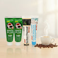 Pack Caffè-Dipendente — 4 dentifrici ÉclatDent: i quattro tubetti su un tavolo in legno chiaro con una tazza di espresso fumante e chicchi di caffè sparsi
