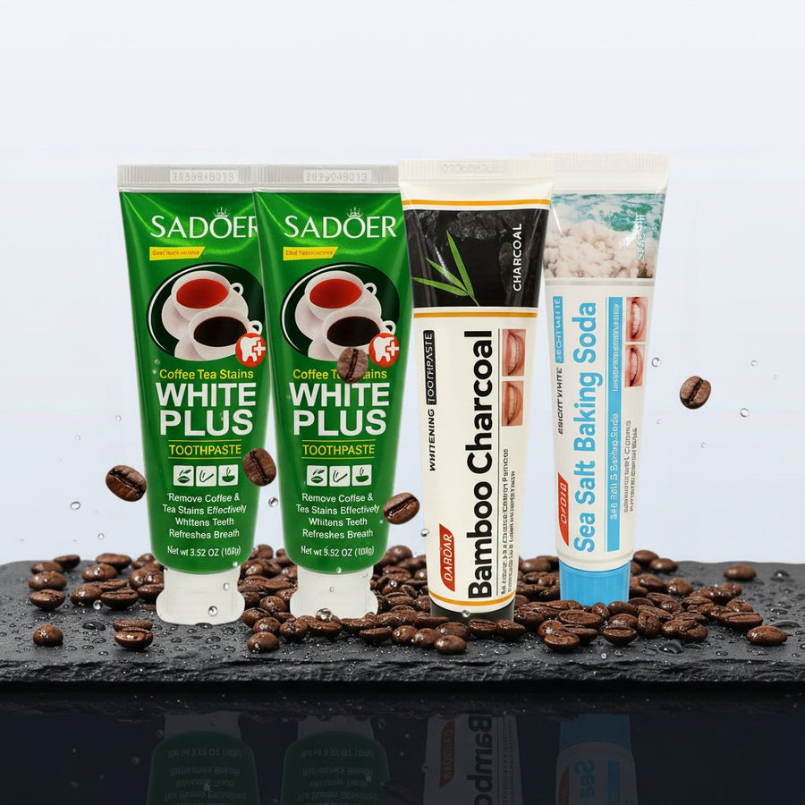Pack Caffè-Dipendente — 4 dentifrici ÉclatDent: i quattro dentifrici SADOER distesi su ardesia nera bagnata di gocce d'acqua, con chicchi di caffè tostato