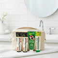 Pack Splendore Carbone — 4 dentifrici ÉclatDent: i quattro tubetti riposti in un beauty case beige su un asciugamano bianco