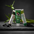 Pack Splendore Carbone — 4 dentifrici ÉclatDent: i quattro tubetti su un tavolo di ardesia grezza con pezzi di carbone attivo e bambù fresco
