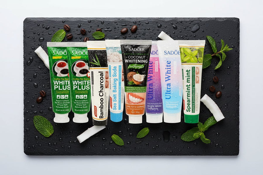Complete Collection Pack — 8 toothpastes ÉclatDent: the eight SADOER toothpastes lying on wet black slate covered in water droplets, with mint leaves, coffee beans and coconut pieces