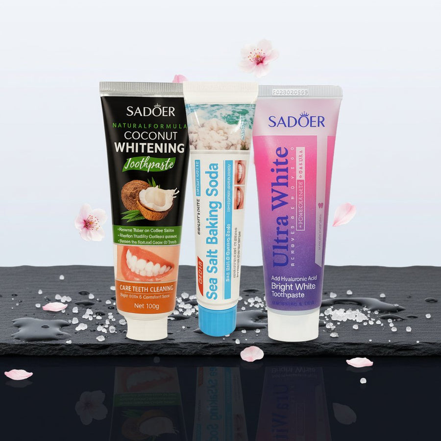 Pack Gengive & Dolcezza — 3 dentifrici ÉclatDent: i tre dentifrici SADOER distesi su ardesia nera bagnata di gocce d'acqua, con petali di ciliegio e cristalli di sale marino