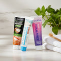 Pack Gengive & Dolcezza — 3 dentifrici ÉclatDent: i tre tubetti su un vassoio di marmo bianco con spazzolino in legno e asciugamano morbido